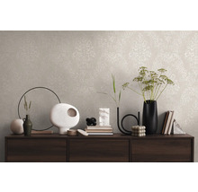 Wandgestaltung mit beiger Tapete und klassischem Muster auf einer Kommode mit dekorativen Vasen und Büchern