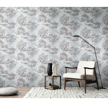 Une pièce avec du papier peint à motifs de nuages, un fauteuil, un lampadaire et une table d''appoint.