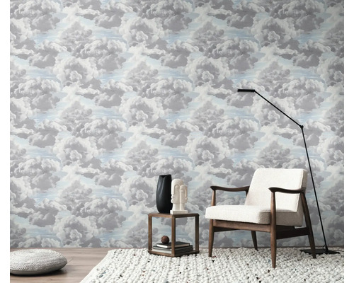 Ein Zimmer mit Wolkenmustertapete, einem Sessel, einer Stehlampe und einem Beistelltisch.