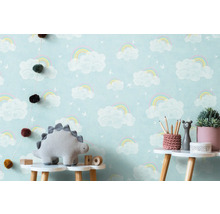 Kinderzimmer mit Wolken-Regenbogen-Tapete, Dinosaurier-Stofftier und Dekoration auf einem Tisch