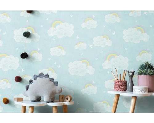 Kinderzimmer mit Wolken-Regenbogen-Tapete, Dinosaurier-Stofftier und Dekoration auf einem Tisch