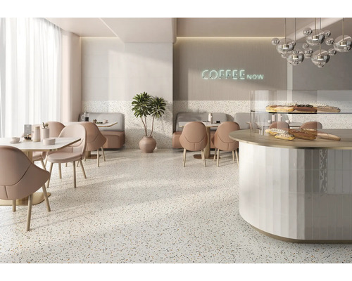 Innenansicht eines Cafés mit Tischen, Stühlen, einer Theke und einem Terrazzoboden.