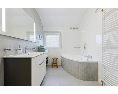 Salle de bains avec lavabo, miroir, baignoire et radiateur