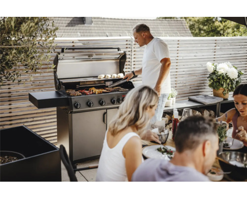 Des personnes font des grillades sur un barbecue à gaz à l''extérieur.
