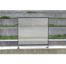 Pare-vent en verre avec cadre métallique devant un escalier en béton