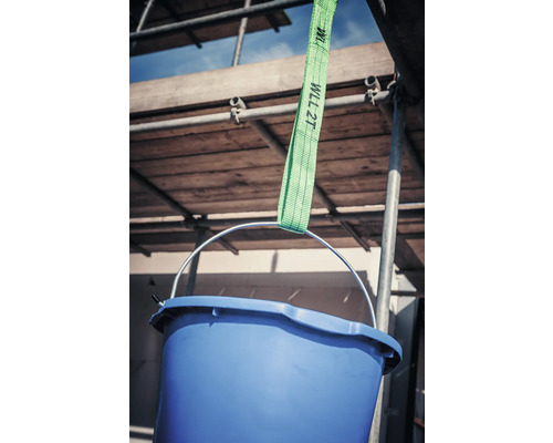 Seau bleu suspendu à une sangle de levage verte devant un échafaudage.