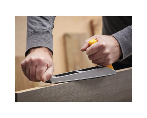 Eine Person benutzt eine Hobelraspel zum Bearbeiten eines Holzstücks.