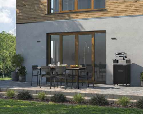 Aussenbereich mit Esstisch, Stühlen und Pizzaofen vor einer Hauswand