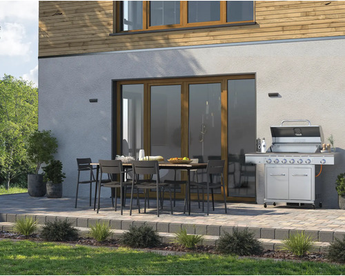 Terrasse mit Grill, Gartentisch und Stühlen vor Hausfassade