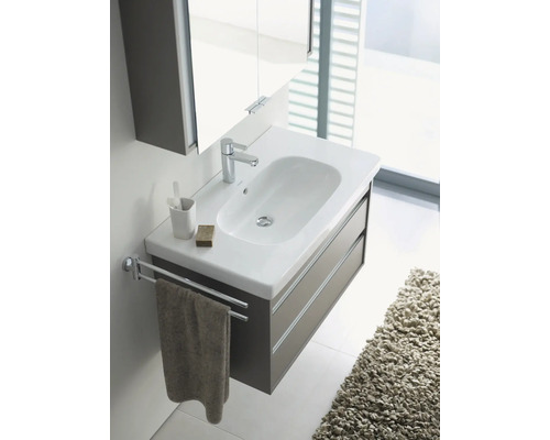 Lavabo avec meuble sous-vasque, robinetterie, porte-serviettes et accessoires de salle de bain dans une salle de bain.