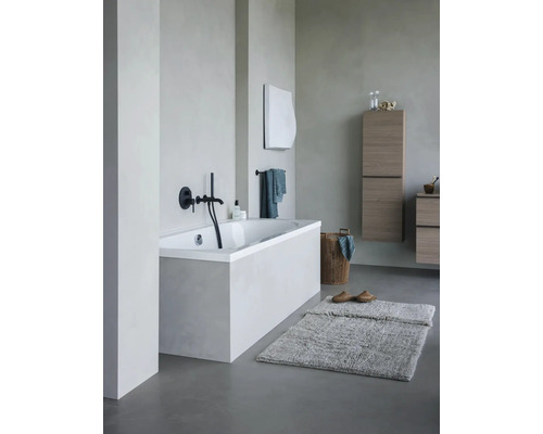 Salle de bain lumineuse avec baignoire, meubles de salle de bain et tapis de bain