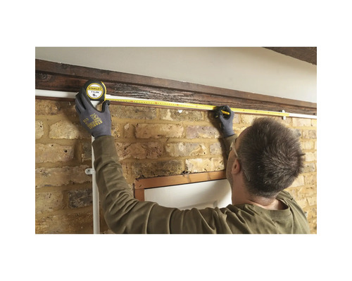 Eine Person misst mit einem Maßband die Länge einer Wand.