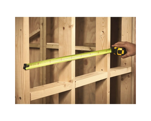 Une personne mesure un cadre en bois avec un mètre ruban.