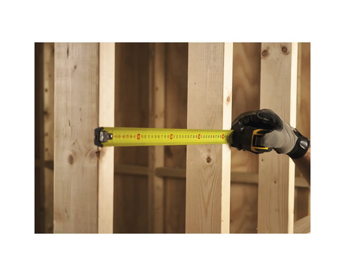 Person misst mit einem gelben Rollbandmass zwischen zwei Holzpfosten