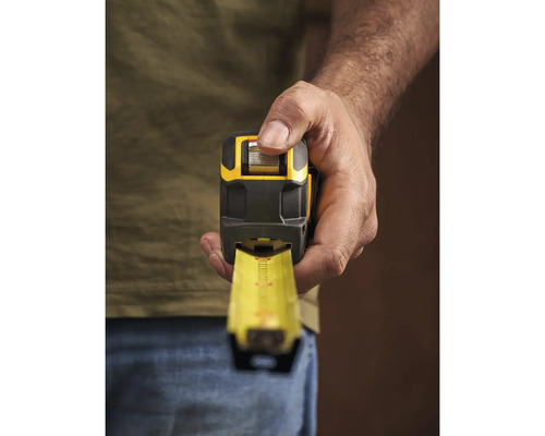 Une personne tient un mètre ruban jaune et noir.