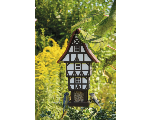 Vogelhaus im Fachwerkhausstil mit zwei Blaumeisen im Garten
