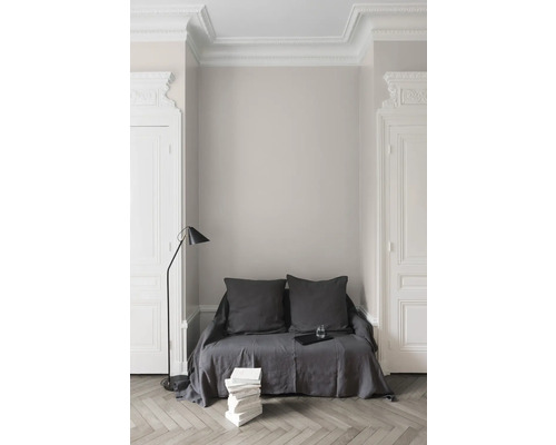 Helles Zimmer mit Sofa, Stehlampe und Stuckverzierungen