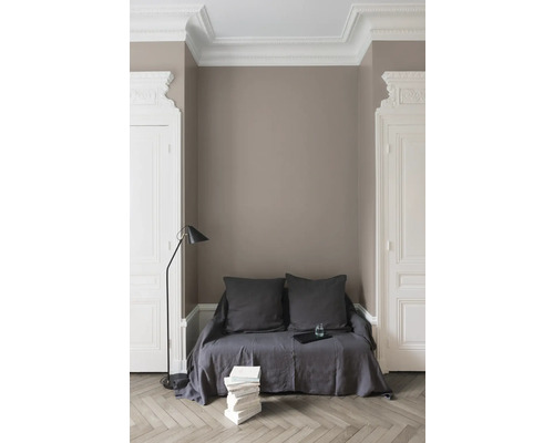 Elegantes Interieur mit Couch, Stehlampe und Bücherstapel vor einer Wand