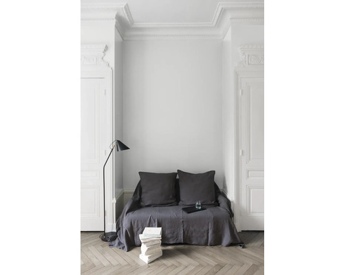 Wohnzimmerszene mit Sofa, Kissen, Stehlampe und Bücherstapel auf Parkettboden