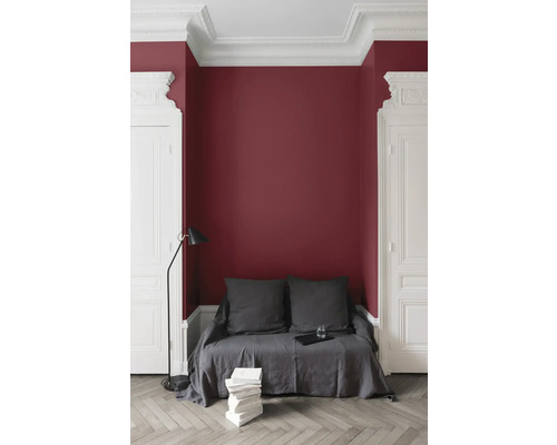 Pièce avec mur bordeaux, canapé avec coussins et lampadaire