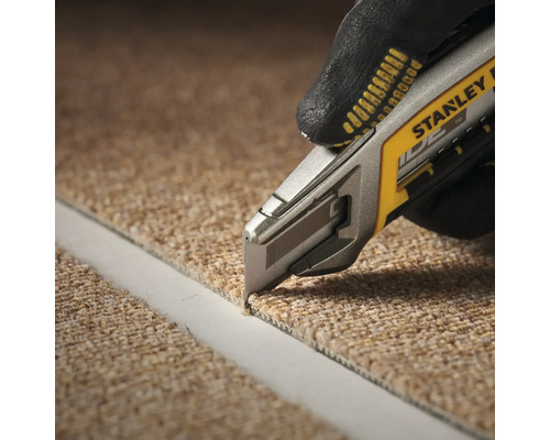 Eine Person schneidet mit einem Teppichmesser Teppich zu. Das Teppichmesser ist von Stanley.