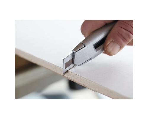 Ein Cuttermesser schneidet eine Platte.