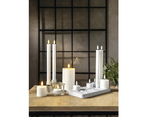 Scène décorative avec différentes bougies LED sur une table en bois.