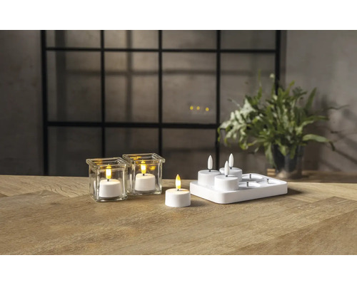 Bougies LED avec verres et station de charge sur une table