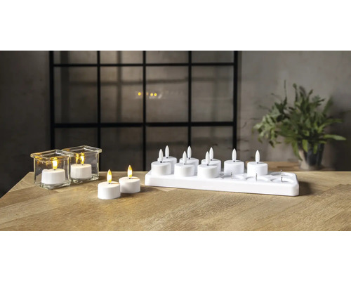 Bougies chauffe-plat décoratives à LED avec piles et station de charge sur une table.