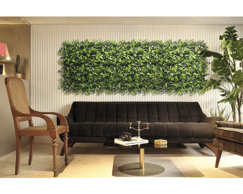 Intérieur décoratif avec panneau mural végétal au-dessus d''un canapé noir.