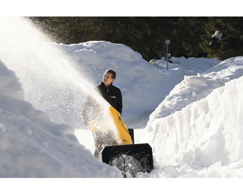 Eine Person benutzt eine Schneefräse, um einen Weg von Schnee zu befreien.