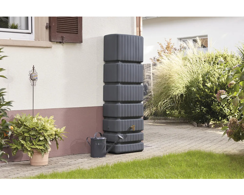 Grauer Regenwassertank mit Giesskanne im Garten