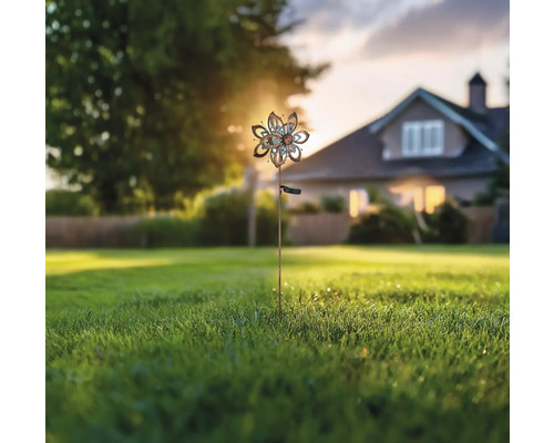 Windspiel mit Solarpanel im Garten vor einem Wohnhaus