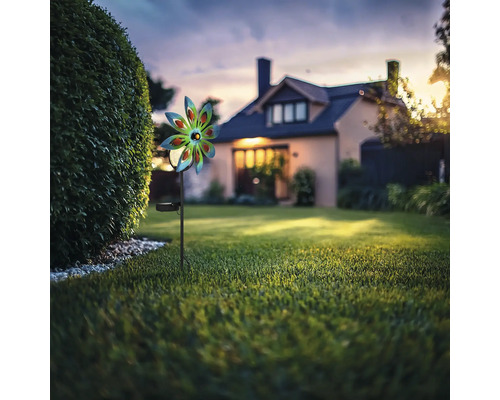 Piquet de jardin solaire avec jeu de moulin à vent dans le jardin devant une maison.