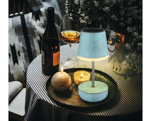 Dekorative Szene mit Tischleuchte, Kerzen, Wein und Blumenvase für gemütliche Atmosphäre.