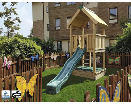 Maison de jeu en bois avec toboggan sur une pelouse, entourée d''une clôture avec des motifs de papillons