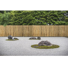 Jardin zen avec clôture en bambou et pierres sur gravier
