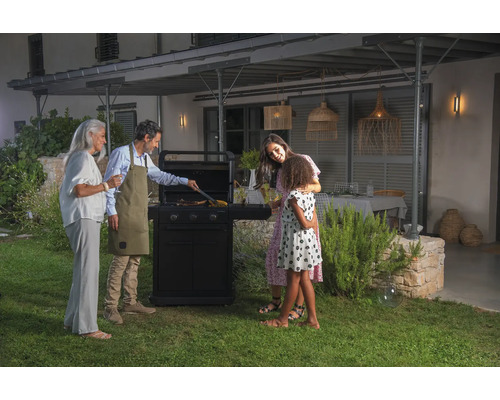 Eine Familie grillt auf einem Gasgrill im Garten.