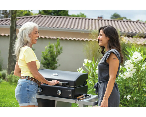 Deux femmes se tiennent à l''extérieur à côté d''un barbecue à gaz Campingaz.