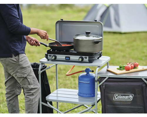 Scène de camping avec réchaud à gaz, ustensiles de cuisine, réservoir de gaz et table de cuisson en extérieur