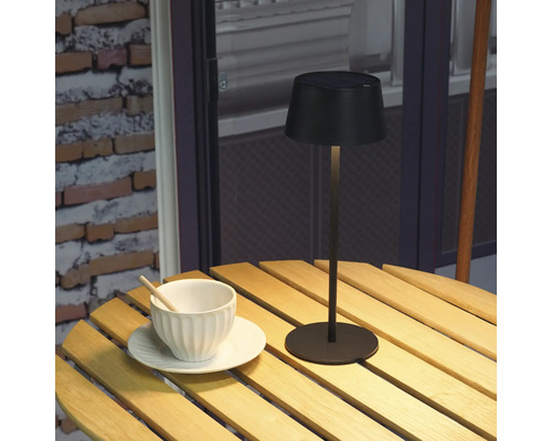 Solarleuchte auf Holztisch mit Tasse und Untertasse