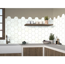 Scène de cuisine avec des carreaux hexagonaux blancs sur le mur, complétée par une étagère en bois et un plan de travail