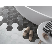 Salle de bain avec carrelage hexagonal, baignoire, serviette et chaussons