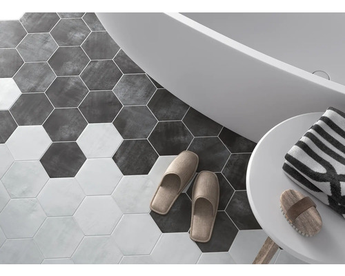 Salle de bain avec carrelage hexagonal, baignoire, serviette et chaussons