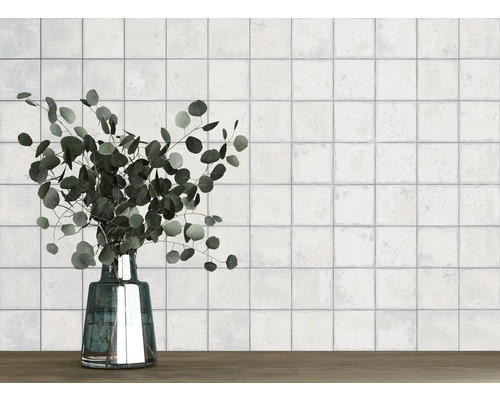 Mur avec des carreaux carrés et un vase avec de l''eucalyptus sur une table en bois