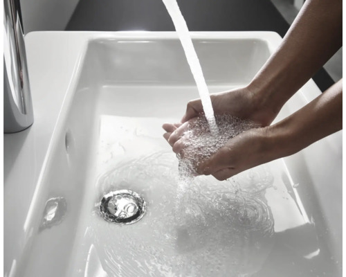 Händewaschen im weissen Keramikwaschbecken mit Wasserhahn