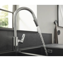 Robinet de cuisine avec douchette extractible et eau courante dans l''évier.