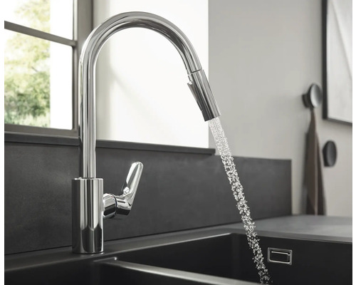 Robinet de cuisine avec douchette extractible et eau courante dans l''évier.