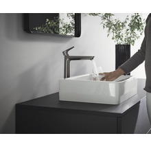 Waschbecken mit Armatur und Person, die ein Glas Wasser füllt