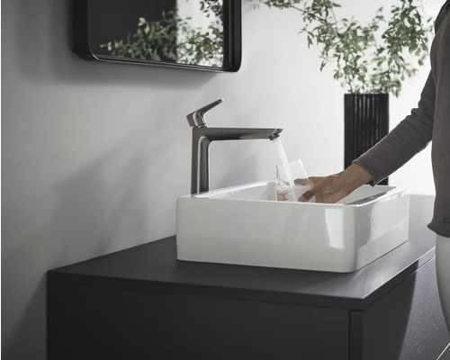 Waschbecken mit Armatur und Person, die ein Glas Wasser füllt